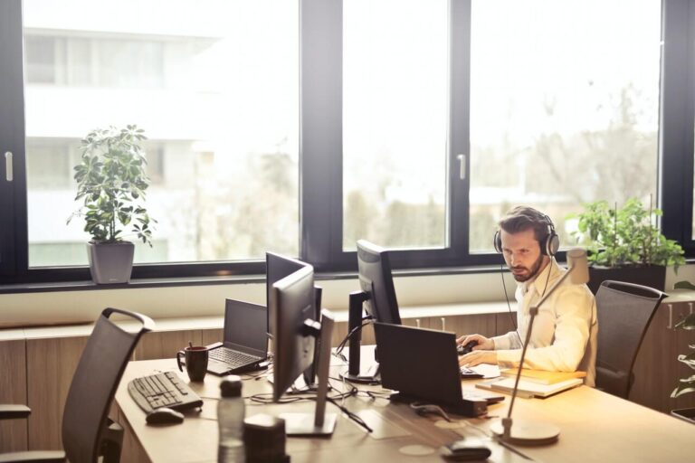 a person sitting at a desk with a laptop and a pen in the hand