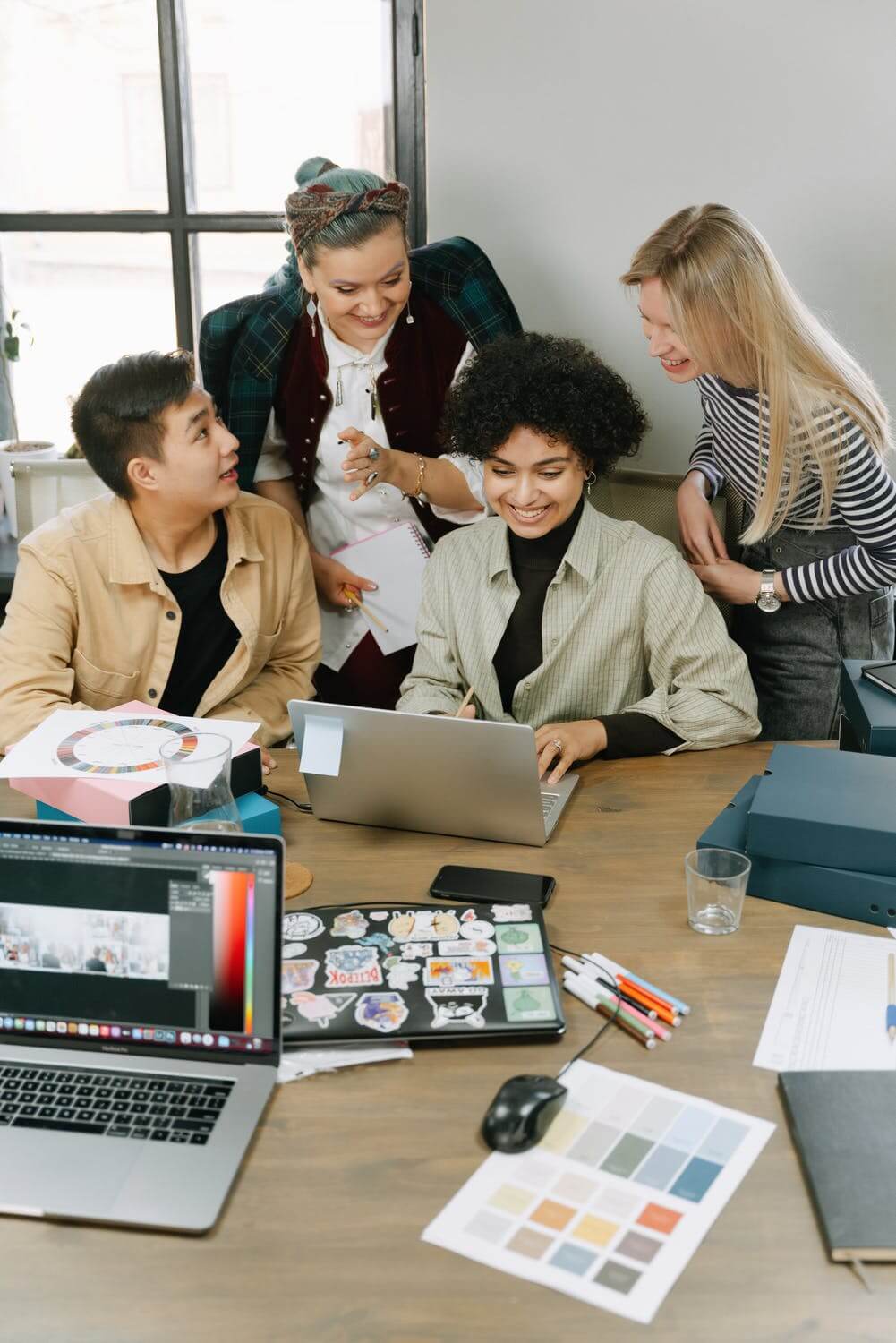 a group of people sitting around a table with laptops and papers